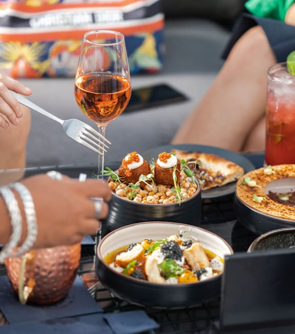 A person is eating a meal with a glass of wine and a drink.