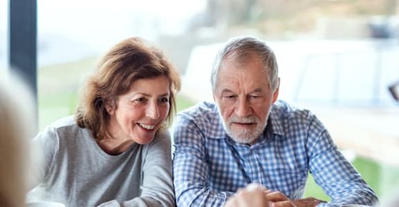an older couple playing a game of chess on a table