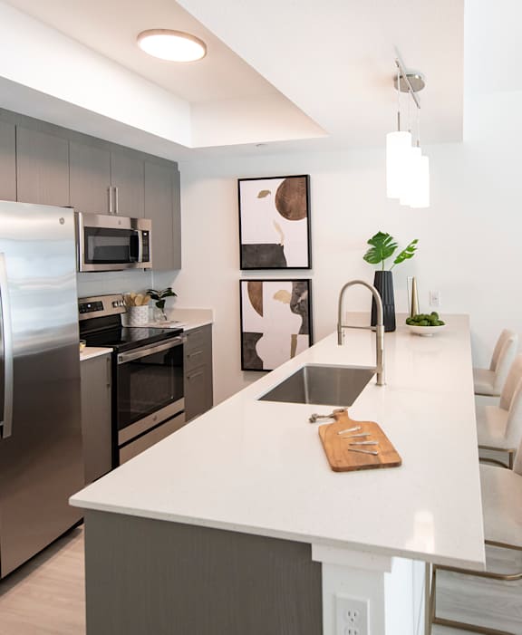 A modern kitchen with a white island and stainless steel appliances.