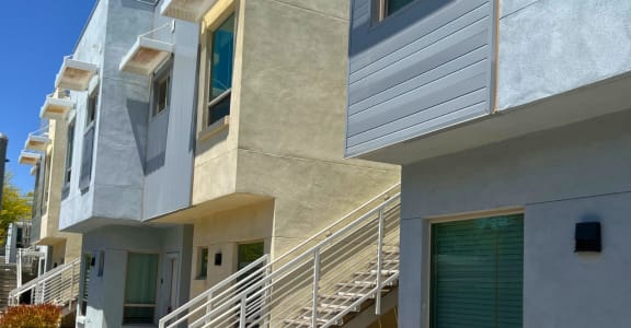 a row of apartments with stairs and balconies on a sunny day