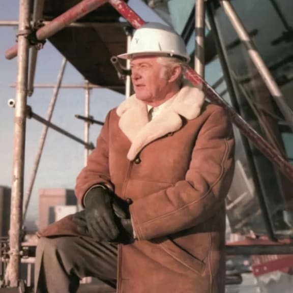 a man wearing a hard hat and a brown coat
