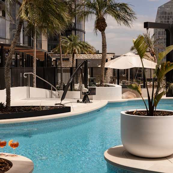 a hotel pool with palm trees and a building in the background