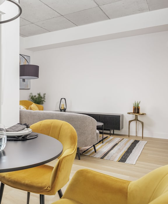A modern living room with a grey sofa, a grey armchair and a yellow chair.