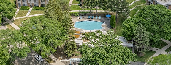 A bird's eye view of a residential area with a swimming pool surrounded by trees.