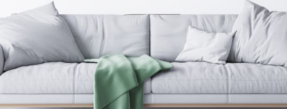 a white couch with white pillows and a green throw