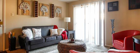 A living room with a black couch and a red chair.
