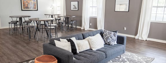 A grey couch with white pillows is in the center of club house