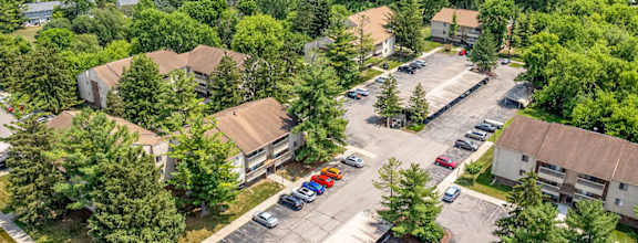A bird's eye view of a parking lot surrounded by trees and buildings.
