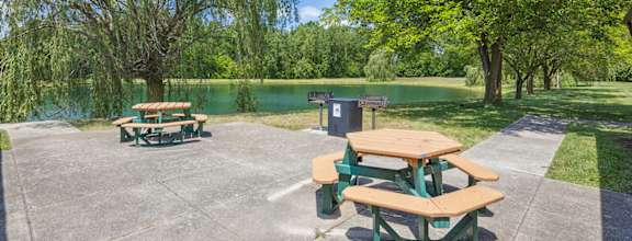 Picnic tables are set up on a patio next to a lake.