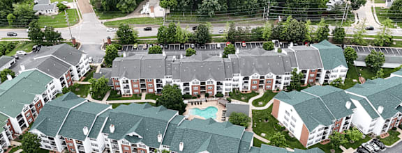 A large building with a green roof is surrounded by smaller buildings with red roofs.