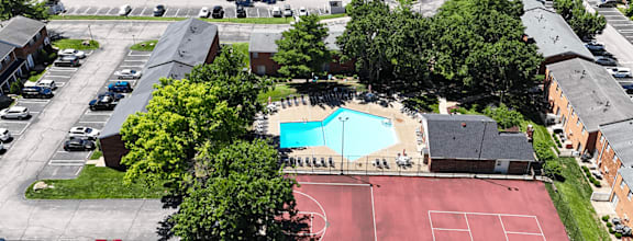 An aerial view of a pool and tennis court surrounded by apartment buildings.