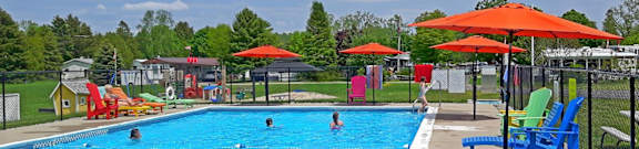 A pool with people swimming and sunshades.