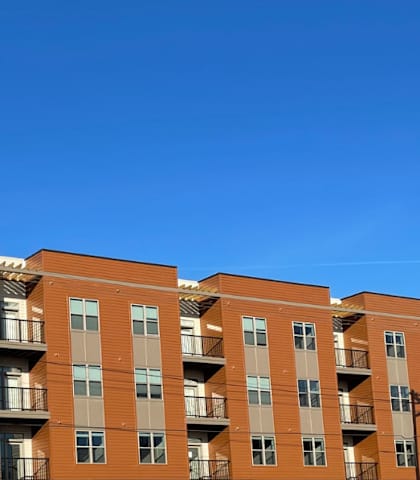 A large apartment building with multiple balconies and doors.