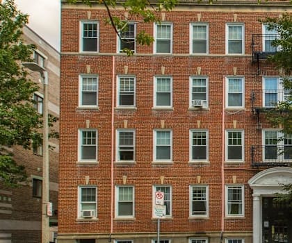A red brick building with a tree in front.