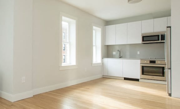 A white room with a wood floor and a window.
