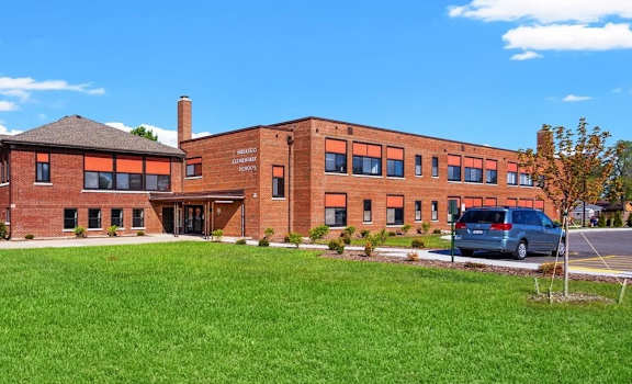 the brick exterior of Muskego School Apartments and a large green space