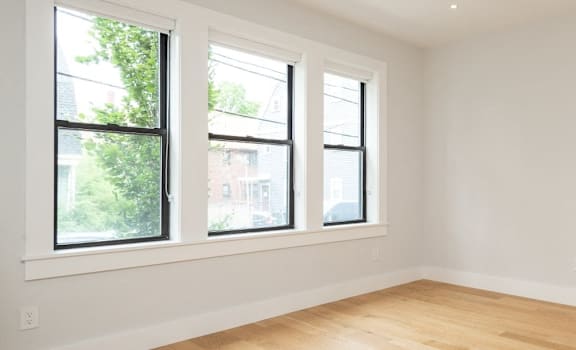 A room with wooden floors and three windows.