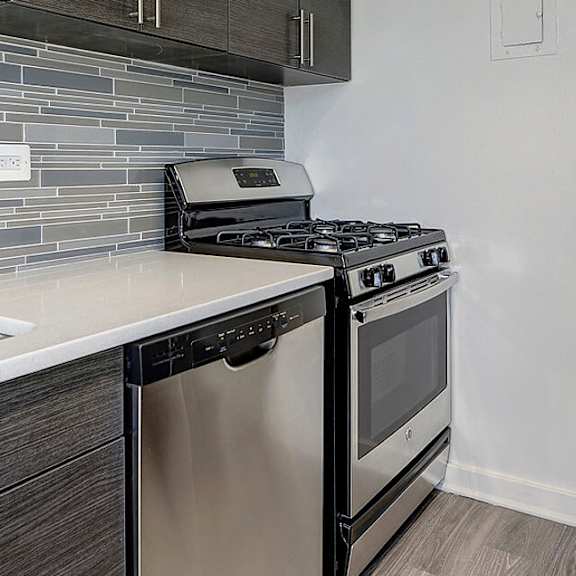 A kitchen with a stove, sink, and refrigerator.