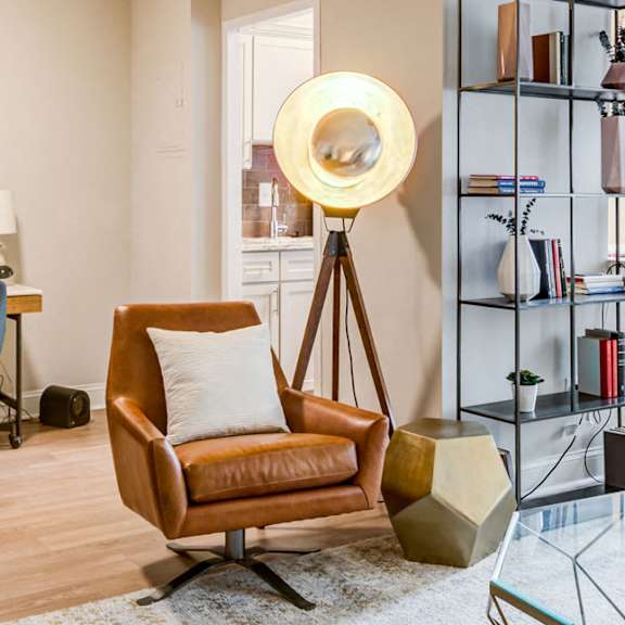 A living room with a chair, a desk, a mirror, and a bookshelf.