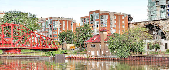 a red bridge over a river in a city with tall buildings, Stonebridge Waterfront, apartments in Downtown Cleveland