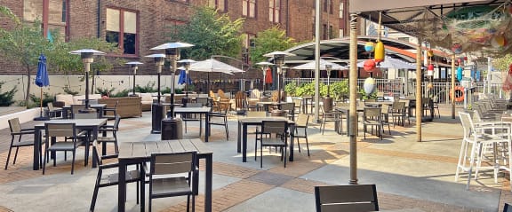 an outdoor patio with tables and chairs and umbrellas at The Residences at 668 Apartments, Ohio