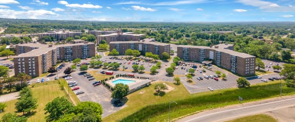 an aerial view of an apartment complex with a pool and parking lot