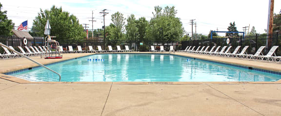 a swimming pool with white chairs around it
