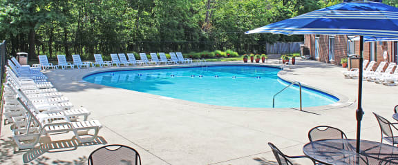 a swimming pool with chairs and an umbrella next to it
