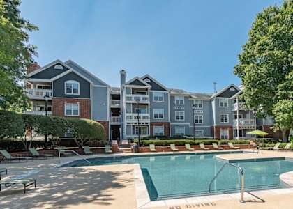 A large swimming pool surrounded by lounge chairs at The Village Apartments, Raleigh, NC