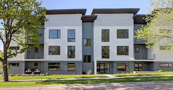 a white and gray building with trees in front of it