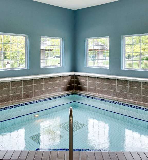A small indoor swimming pool with a tiled wall and windows. at The Preserve at Commerce, Rogers, 55374