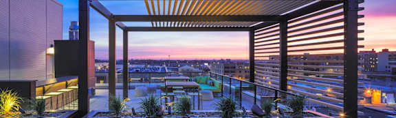 a rooftop terrace with a view of the city at sunset