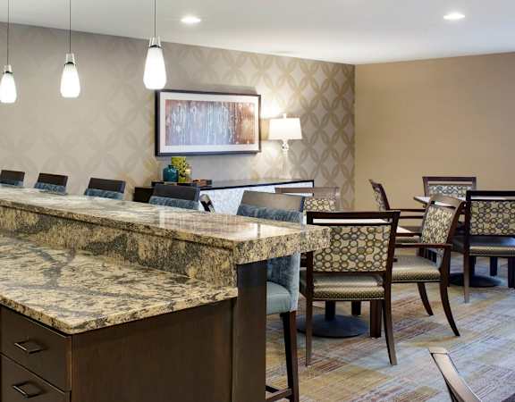 A kitchen with a marble countertop and wooden chairs.