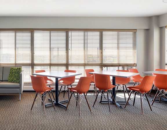 A modern living room with a grey sofa, orange chairs, and a black coffee table. at Park Towers, St. Louis Park, 55416