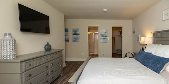 A bedroom with a large bed and a tv mounted on the wall at Deer Park Apartments, Randallstown, 21133