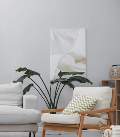 A living room with a white couch, a wooden chair, a wooden table, and a potted plant.
