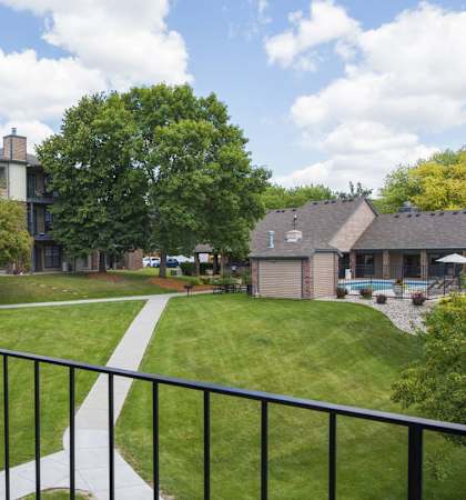A view from a balcony overlooking a green lawn and apartment buildings. at Eden Commons, Eden Prairie, MN, 55344