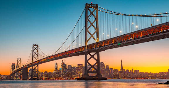 the bay bridge at sunset with the city in the background