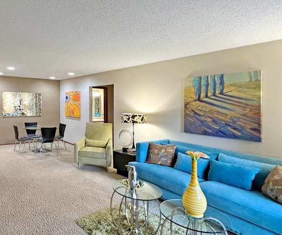 A living room with a blue couch and a painting on the wall.