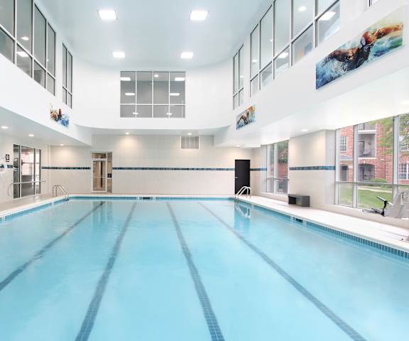 A large indoor swimming pool with a blue tinted water.