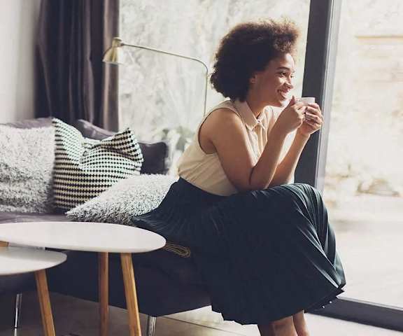 a woman sitting on a couch with a cup of coffee