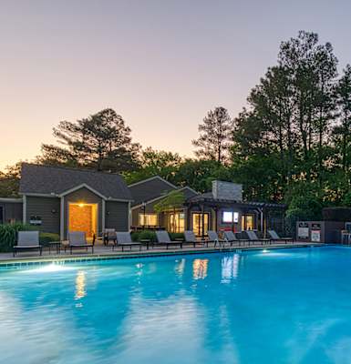a swimming pool at dusk with a house in the background