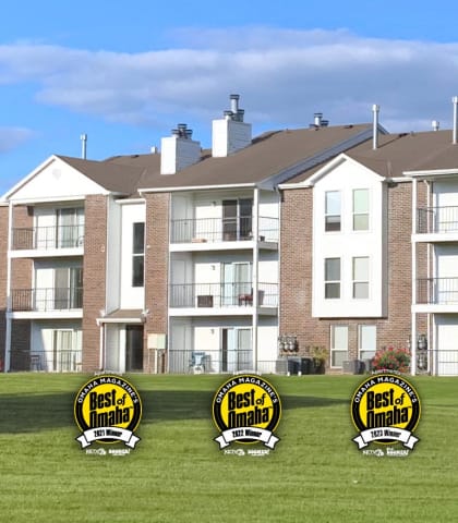 a row of apartments with yellow and white buildings on a green lawn