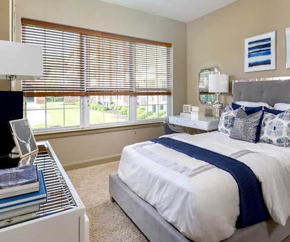 A bedroom with a large bed and a window with blinds.