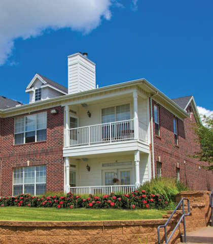 A red brick house with a white balcony and a white chimney.