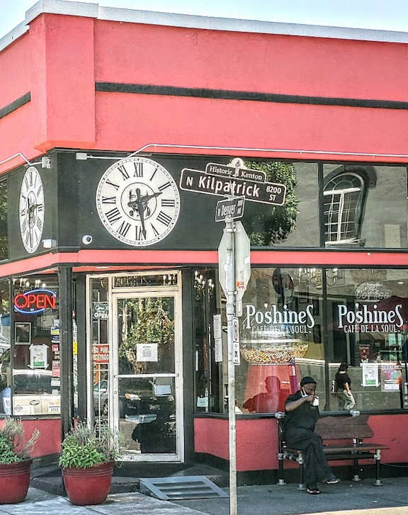 A red building with a clock on the front and Poshine Poshine written on the window.