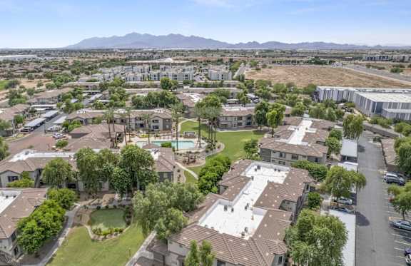 A bird's eye view of a residential neighborhood with houses, trees, and a pool at Adiamo Palm Valley, Goodyear