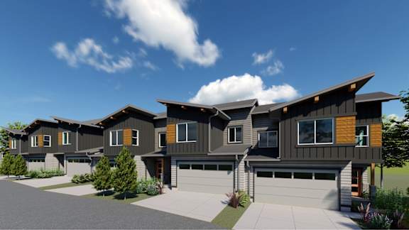 A modern house with a grey and brown exterior and a large front yard.