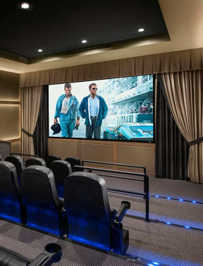 a large screening room with blue chairs and a large screen on the wall