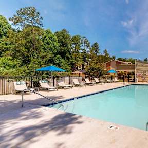 A large outdoor swimming pool surrounded by sun loungers and umbrellas.